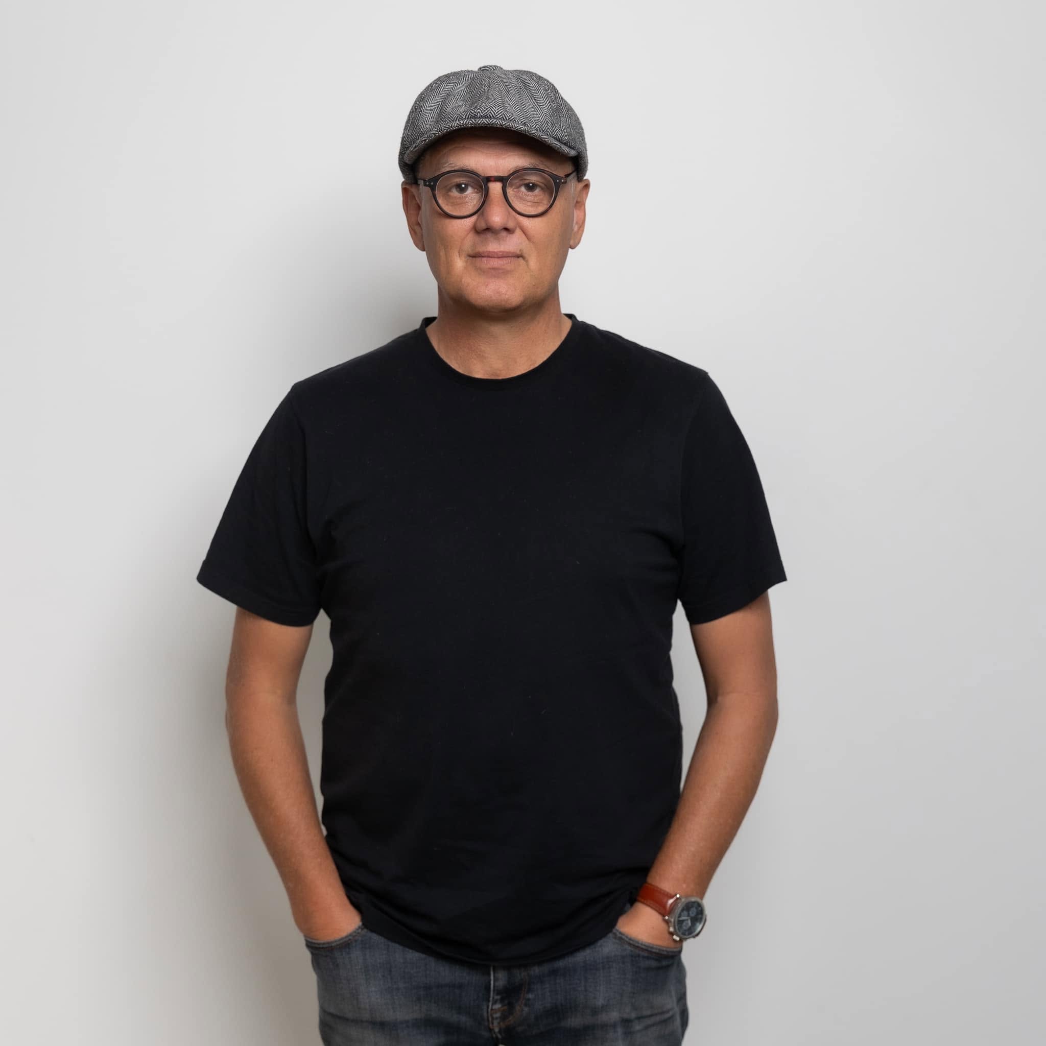 Ryan Edwards — Kāpiti Coast wedding celebrant, MC and musician — in a flat cap and glasses, a relaxed studio portrait