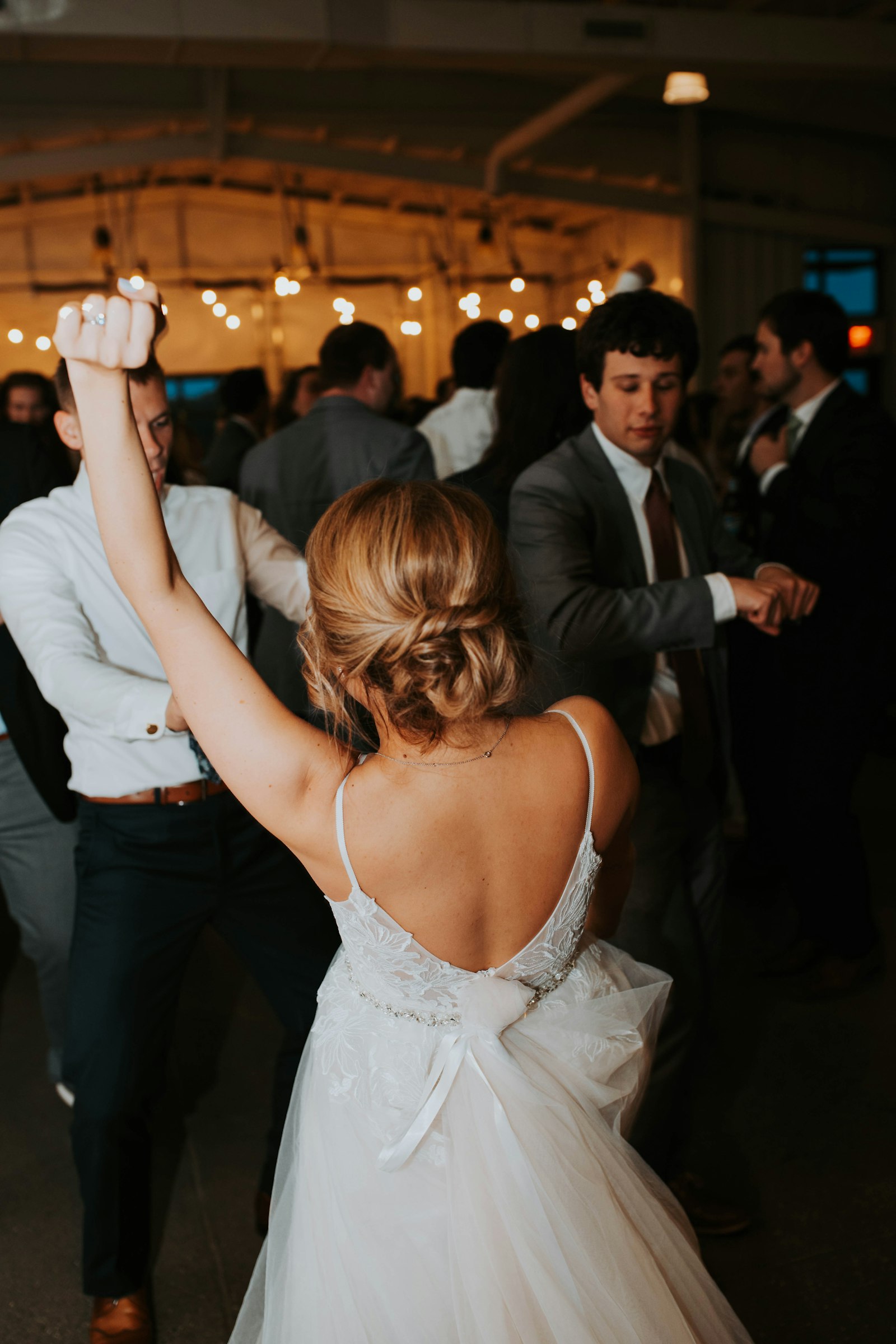 A bride dancing under warm string lights at a wedding reception